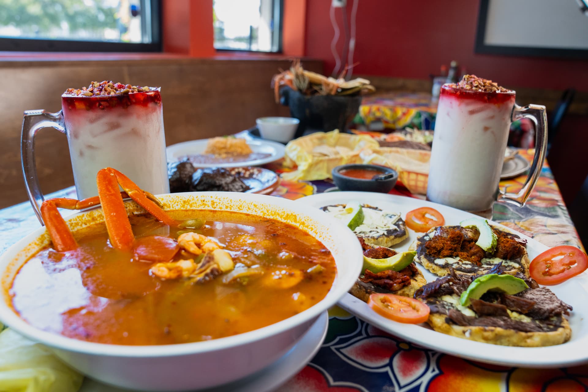 A spread of Oaxacan dishes, including caldo de mariscos and tlayudas, with horchata